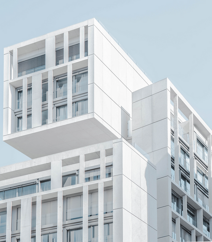 Modern white building with geometric patterns against a clear blue sky. The structure features large windows and creates a minimalist vibe.